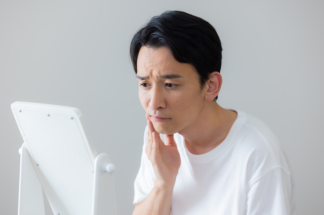 鏡を見ながら気になる様子の男性
