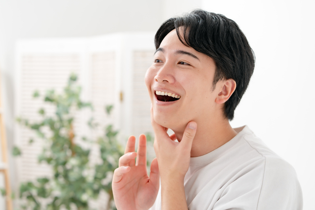 白いTシャツを着て室内で笑っている男性